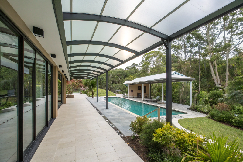 Covered walkway connecting resort-style pool area to entertaining pavilion with weather protection on Sunshine Coast property